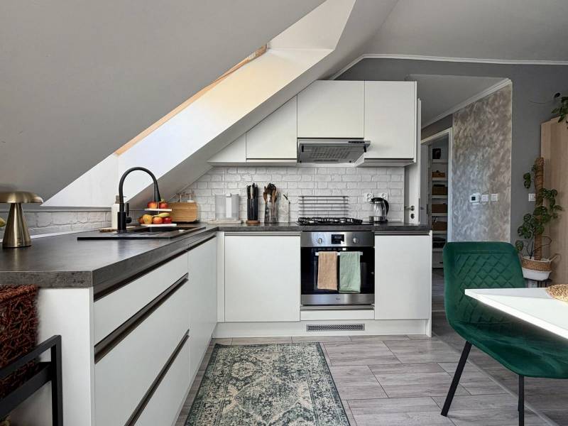 Kuchyně v 2-pokojovém bytě se šikmým stropem a podlahou s dřevěným dekorem.