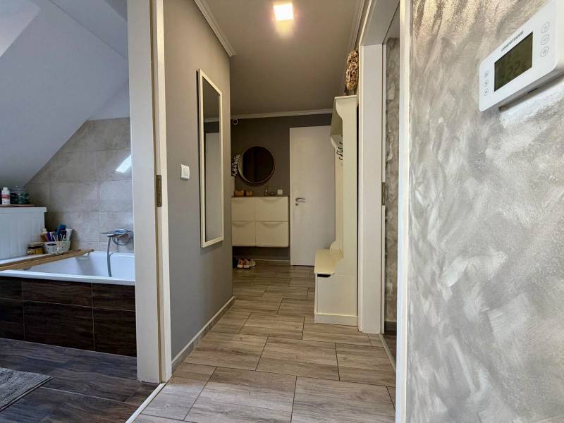 Koupelna v 2-pokojovém bytě s podlahou s dřevěným dekorem a světlými stěnami.