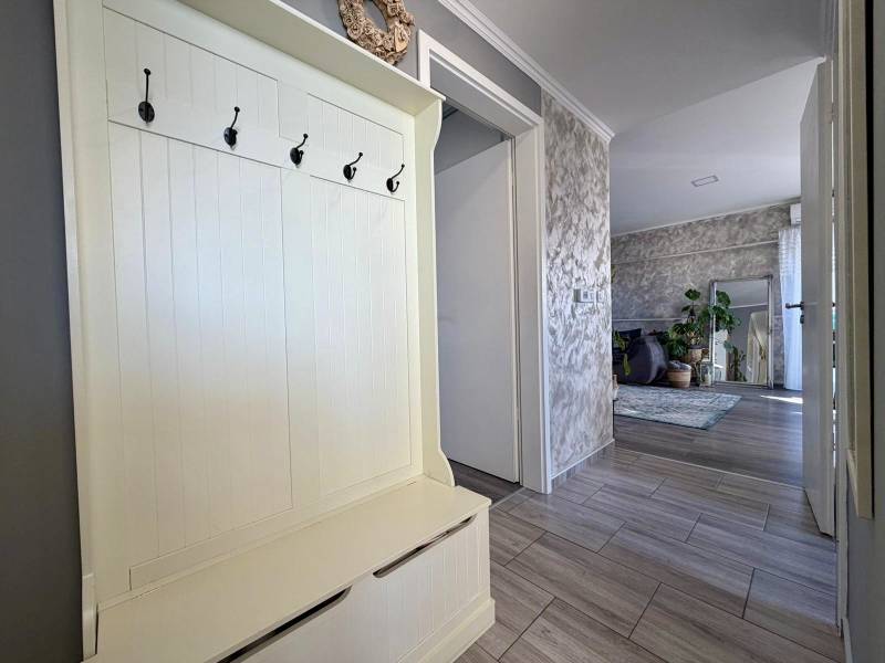 Vstupní chodba v 2pokojovém bytě s věšáky, vedoucí do obývacího pokoje s rostlinami.