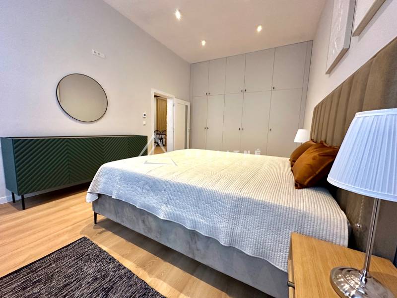 Ložnice ve 2-pokojovém bytě s postelí, skříněmi a podlahou s dřevěným dekorem.