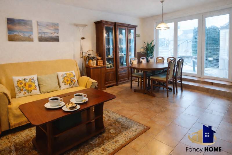 Obývací pokoj v rodinném domě s jídelním stolem, policemi a pohovkou.