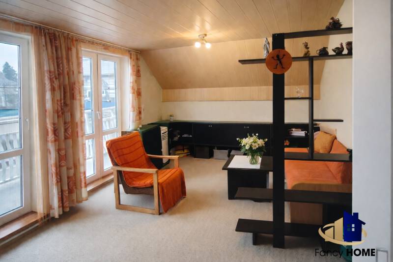 Obývací pokoj s oranžovým křeslem a pohovkou v rodinném domě.