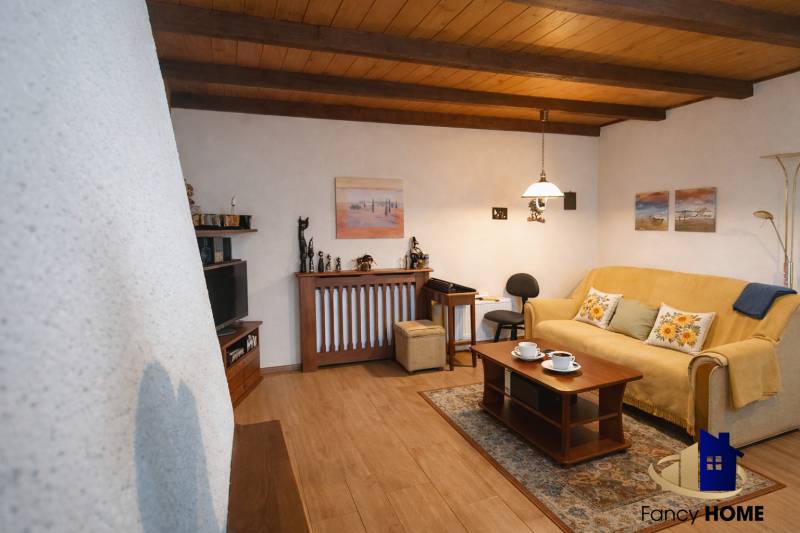 Obývací pokoj v rodinném domě s podlahou s dřevěným dekorem, pohodlnou pohovkou a dekoracemi.