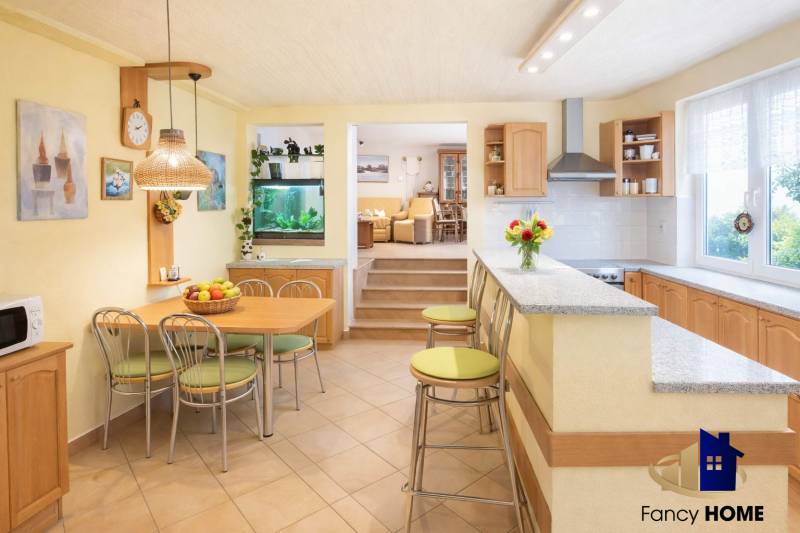 Kuchyně a jídelna s barem v rodinném domě, světlé odstíny a akvárium.