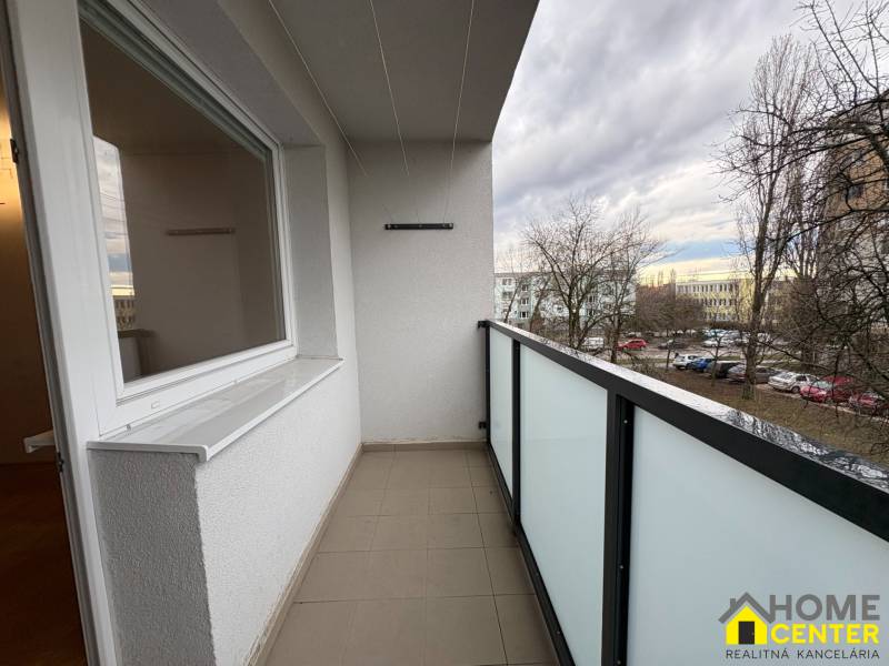 Balkon 3pokojového bytu v Komárně na Košické ulici s výhledem na parkoviště a stromy.