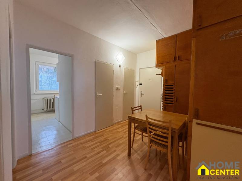 Interiér 3-pokojového bytu s podlahou s dřevěným dekorem, jídelní kout se stolem a židlemi.