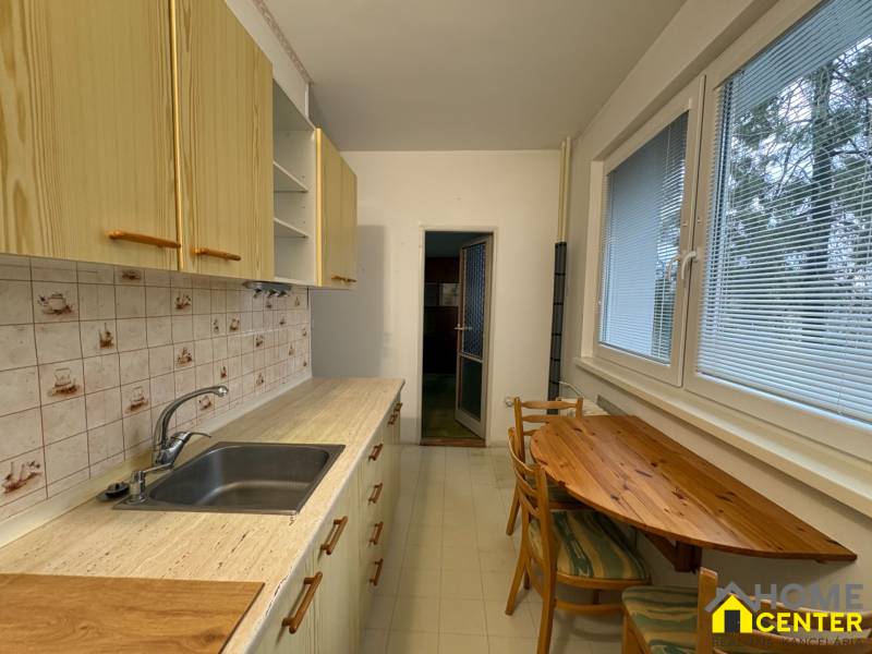 Kuchyně v 3-pokojovém bytě s dřevěným dekorem, dřevěný stůl a kachličkový obklad.