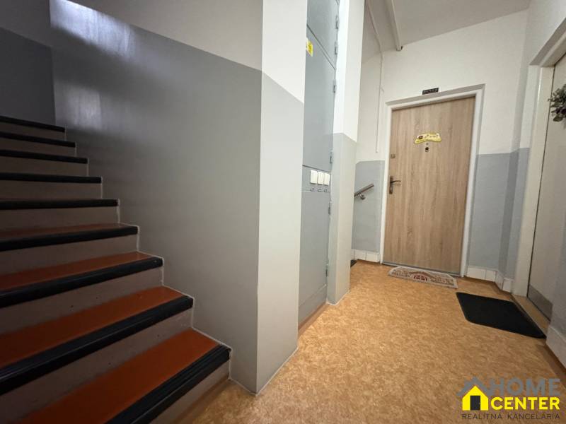 Schodiště a vstupní dveře v 3-pokojovém bytě s podlahou s dřevěným dekorem.