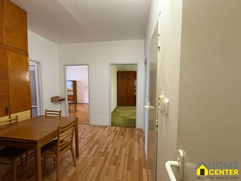 Interiér 3-pokojového bytu s podlahou s dřevěným dekorem, stolem a židlemi.