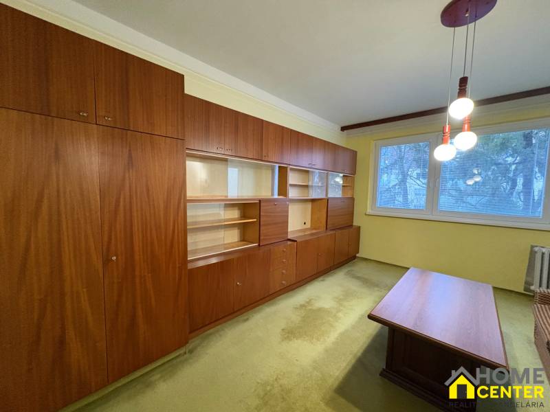 Obývací pokoj s dřevěným nábytkem a kobercem ve 3-pokojovém bytě.