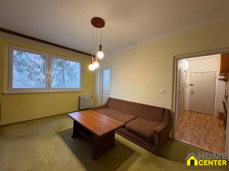 Obývací pokoj v 3pokojovém bytě s pohovkou a stolem.