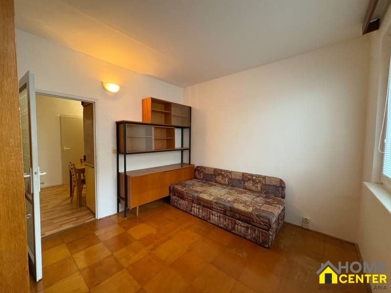 Pokoj v 3-pokojovém bytě s pohovkou, skříňkou a podlahou s dřevěným dekorem.