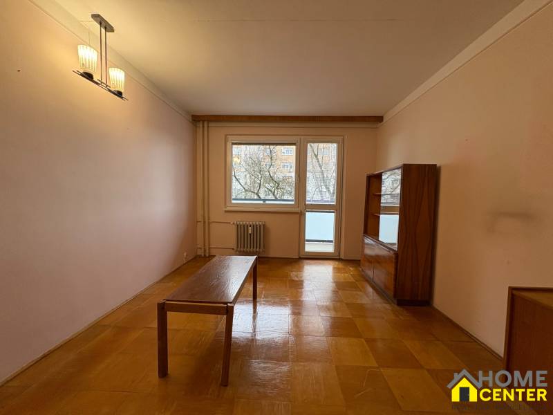 Obývací pokoj ve 3-pokojovém bytě s podlahou s dřevěným dekorem a jednoduchým nábytkem.