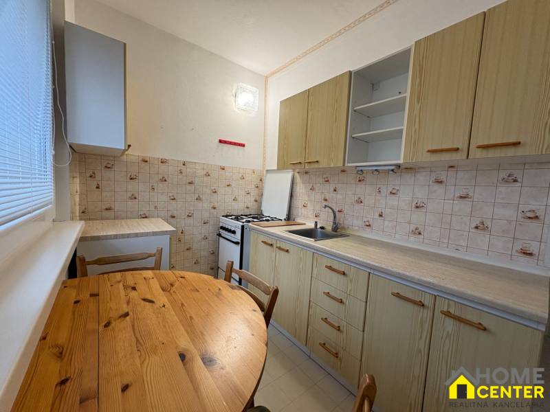 Kuchyně v 3-pokojovém bytě se stolem, dlažbou a útulným prostorem na vaření.