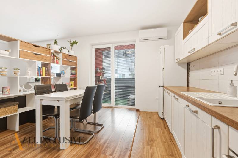 Kuchyně v 2pokojovém bytě s jídelním stolem a podlahou s dřevěným dekorem.