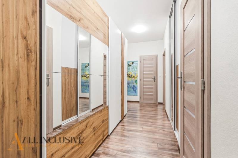 Chodba v 2-pokojovém bytě s podlahou s dřevěným dekorem a zrcadlovou skříní.