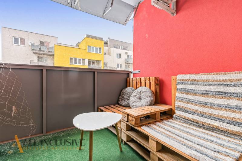 Balkon s paletovým nábytkem a stolkem, barevné budovy ve Vráblech, 2-pokojový byt.