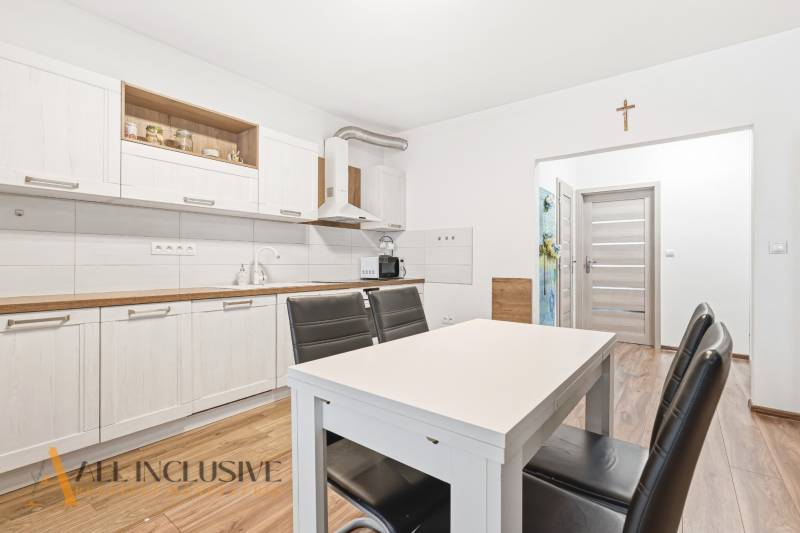 Kuchyně v 2-pokojovém bytě se světlými skříňkami a podlahou s dřevěným dekorem.