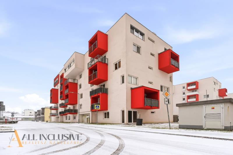 Exteriér bytového domu s červenými balkóny ve Vráblech, ideální pro 2-pokojový byt.