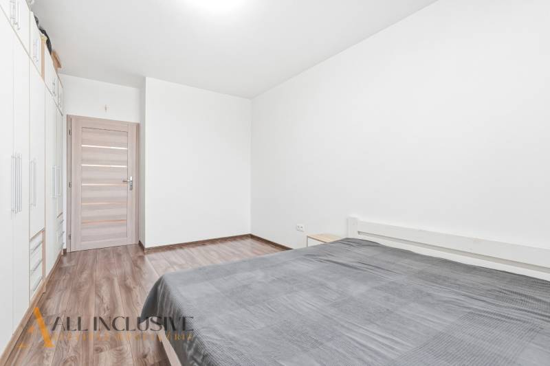 Ložnice v 2pokojovém bytě s podlahou s dřevěným dekorem a prostornou skříní.