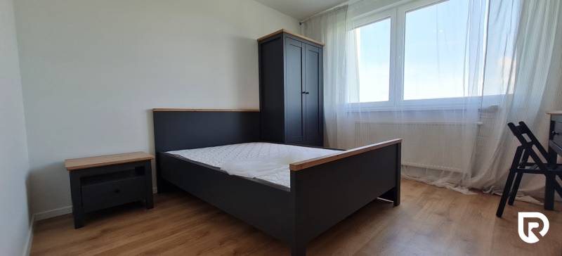 Ložnice s postelí, šatní skříní a podlahou s dřevěným dekorem v 2-pokojovém bytě.