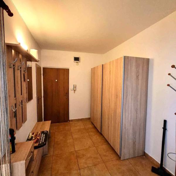 Předsíň v 2-pokojovém bytě s věšáky, skříní a podlahou s dřevěným dekorem.