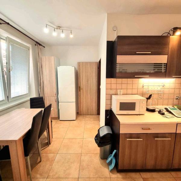 Kuchyně v 2-pokojovém bytě s jídelním stolem a spotřebiči.