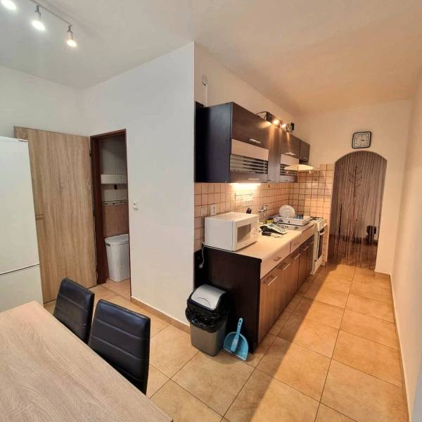 Kuchyně v 2pokojovém bytě s dlažbou, dřevěným dekorem a zařízením.