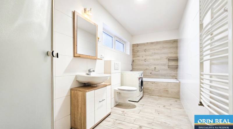 Koupelna v rodinném domě s podlahou s dřevěným dekorem a pračkou.