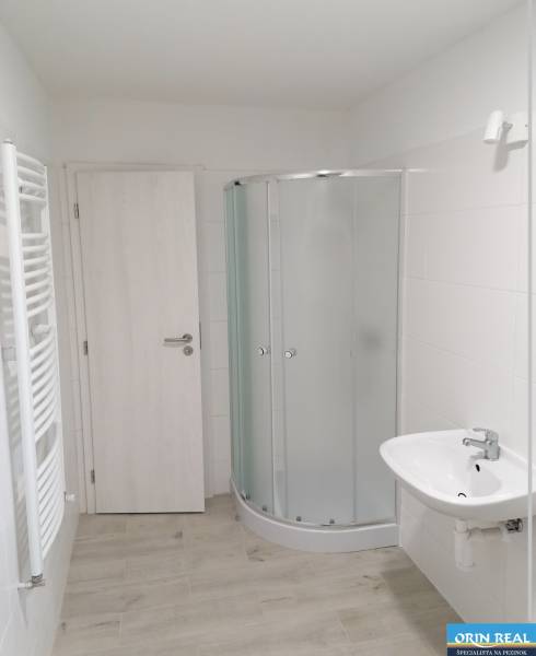 Koupelna v rodinném domě s bílým sprchovým koutem a světlou podlahou s dřevěným dekorem.