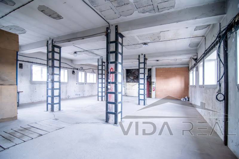 Průmyslový interiér sklady a haly s betonovými stěnami a železnými nosníky.