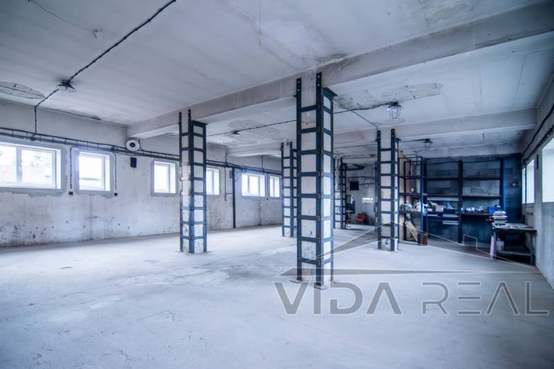 Prostory se sloupy a okny využívané jako sklady a haly.