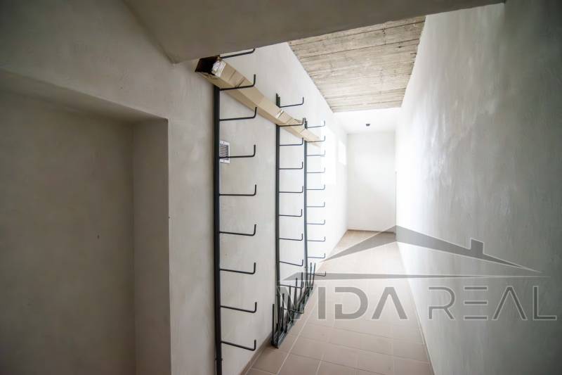 Úzký interiérový prostor ve skladu s kovovými věšáky na stěně.