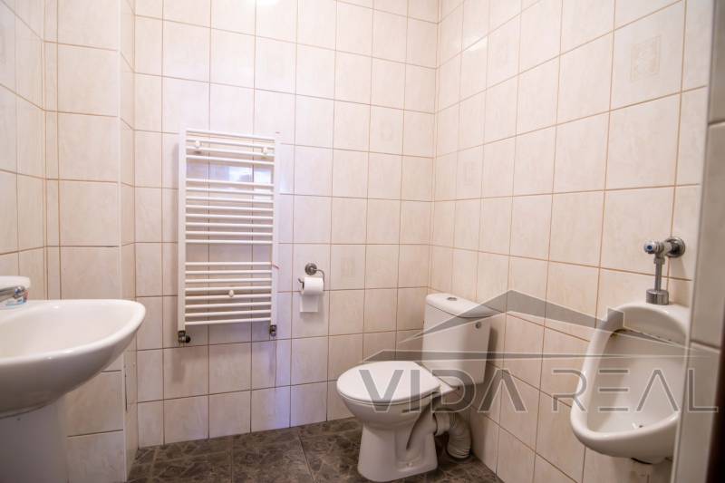 Koupelna ve skladech a halách s toaletou, pisoárem a radiátorem na stěně.