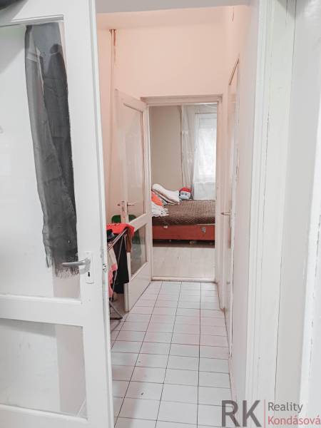 Úzká bílá chodba vede k dětskému pokoji s postelí v rodinném domě.