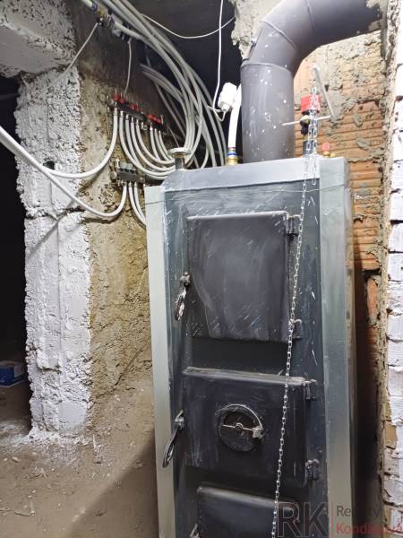 Kotelná v rodinném domě s potrubím a topným systémem.