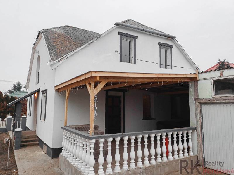 Rodinný dům ve Vizsoly s terasou, bílou fasádou a dřevěným přístřeškem.