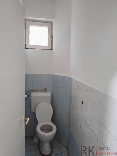 Koupelna v rodinném domě s modrými obklady a malým oknem.