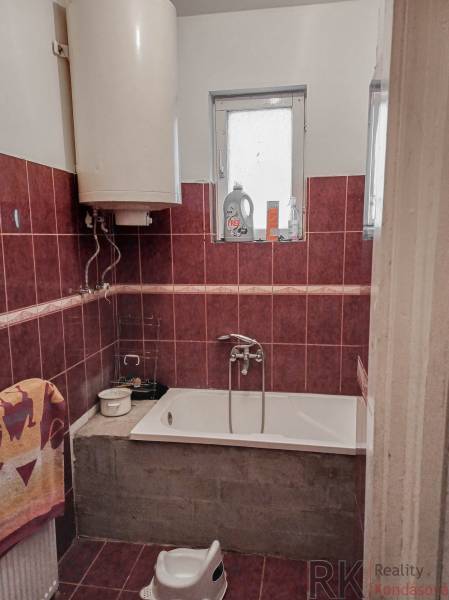 Koupelna v rodinném domě se sprchou, vanou, oknem a bojlerem.