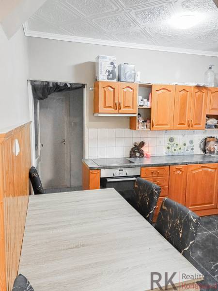 Kuchyně v rodinném domě s dřevěnými skříňkami a stropním obkladem.