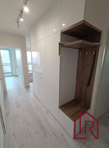 Chodba v 3-pokojovém bytě s bílými skříněmi a vestavěnou šatní skříní s dřevěným dekorem.