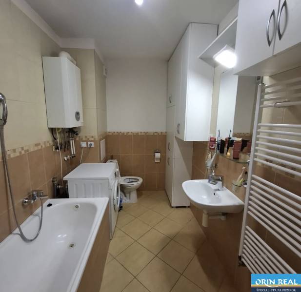 Koupelna v 2-pokojovém bytě s vanou, pračkou a zásobníkem teplé vody.