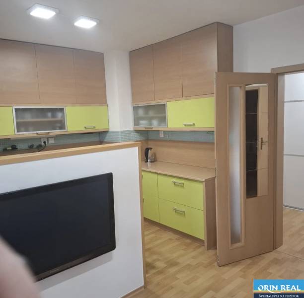 Kuchyně v 2pokojovém bytě s podlahou s dřevěným dekorem a barevnými skříňkami.