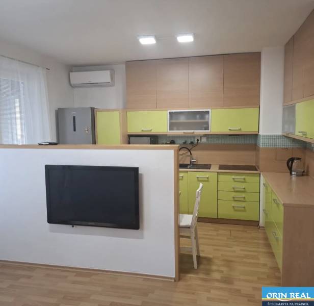 Kuchyně v 2-pokojovém bytě s podlahou s dřevěným dekorem a zelenými skříňkami.