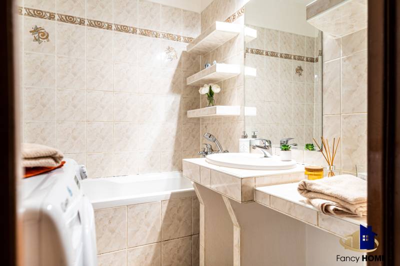 Koupelna s rohy v 3-pokojovém bytě, se sprchou, umyvadlem a pračkou.