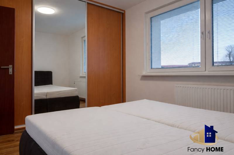 Ložnice v 3pokojovém bytě s velkým oknem, vestavěnou skříní a postelí.