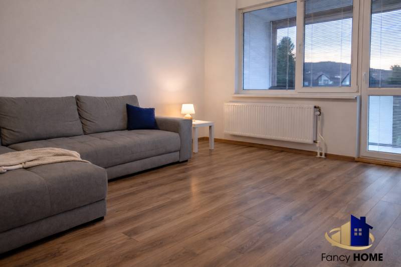 Obývací pokoj v 3pokojovém bytě s pohovkou a podlahou s dřevěným dekorem.