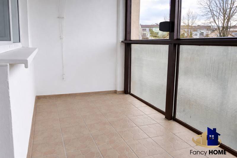 Zasklený balkon 3pokojového bytu, podlaha s dlažbou, výhled na okolí.