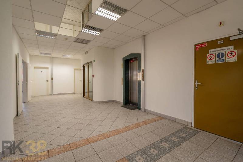 Kanceláře s výtahem a dlažbou, neutrální barvy a moderní osvětlení.
