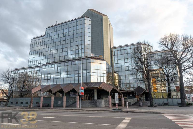 Prosklená budova kanceláří ve městě Poprad s minimalistickým designem a městským okolím.